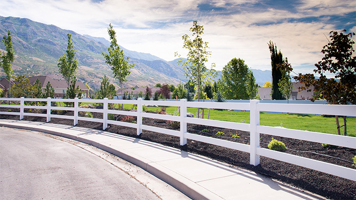White three-rail ranch rail vinyl fence adjacent to a road, some of our white vinyl fence panels near Gardena, CA.