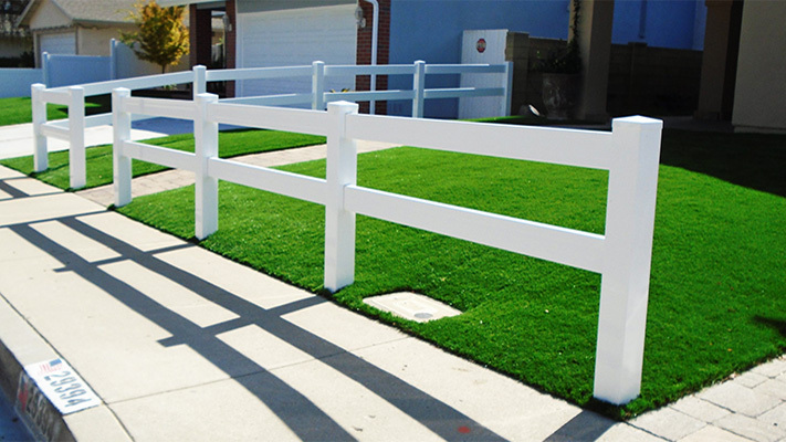 White two-rail ranch rail fence in front of a home, some of our property management fencing for houses in Burrel, California.
